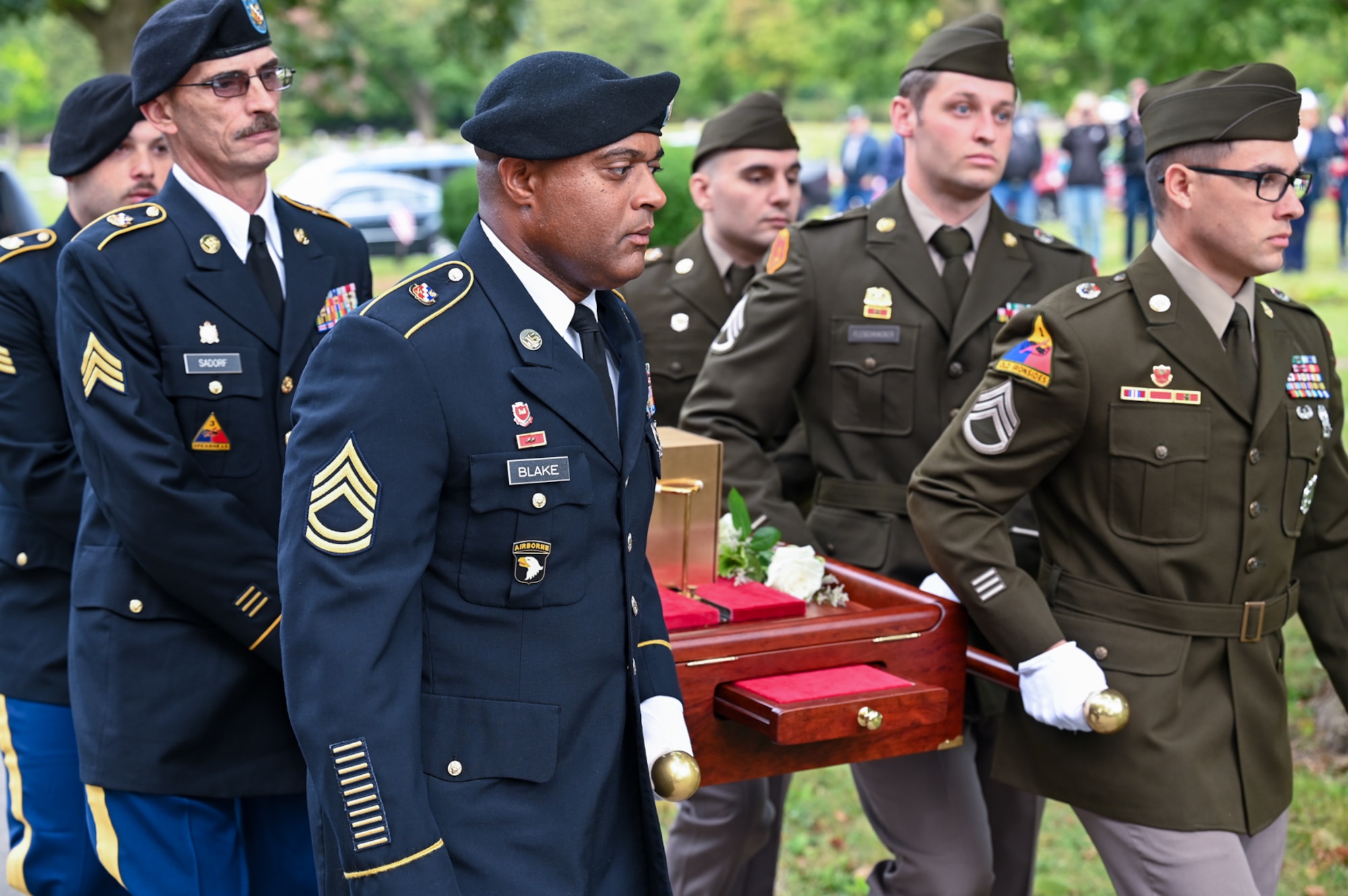 Men in military unforms carry remains at a burial