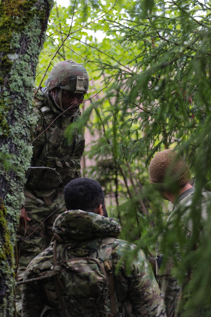 U.S. Army Spc. Olu Achu, a forward observer (left), Spc. Derrick Hyman, a radio telephone operator, Sgt. Kyle Troyer, a forward observer, with 1st Battalion, 107th Field Artillery, Detachment 1, Maryland Army National Guard, move through the woods while awaiting air support during Exercise Hedgehog near Võru, Estonia, May 14, 2025.