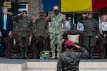 Adm. Holsey and Guatemalan service member leaders salute on a stage