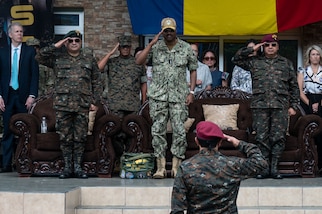 Adm. Holsey and Guatemalan service member leaders salute on a stage