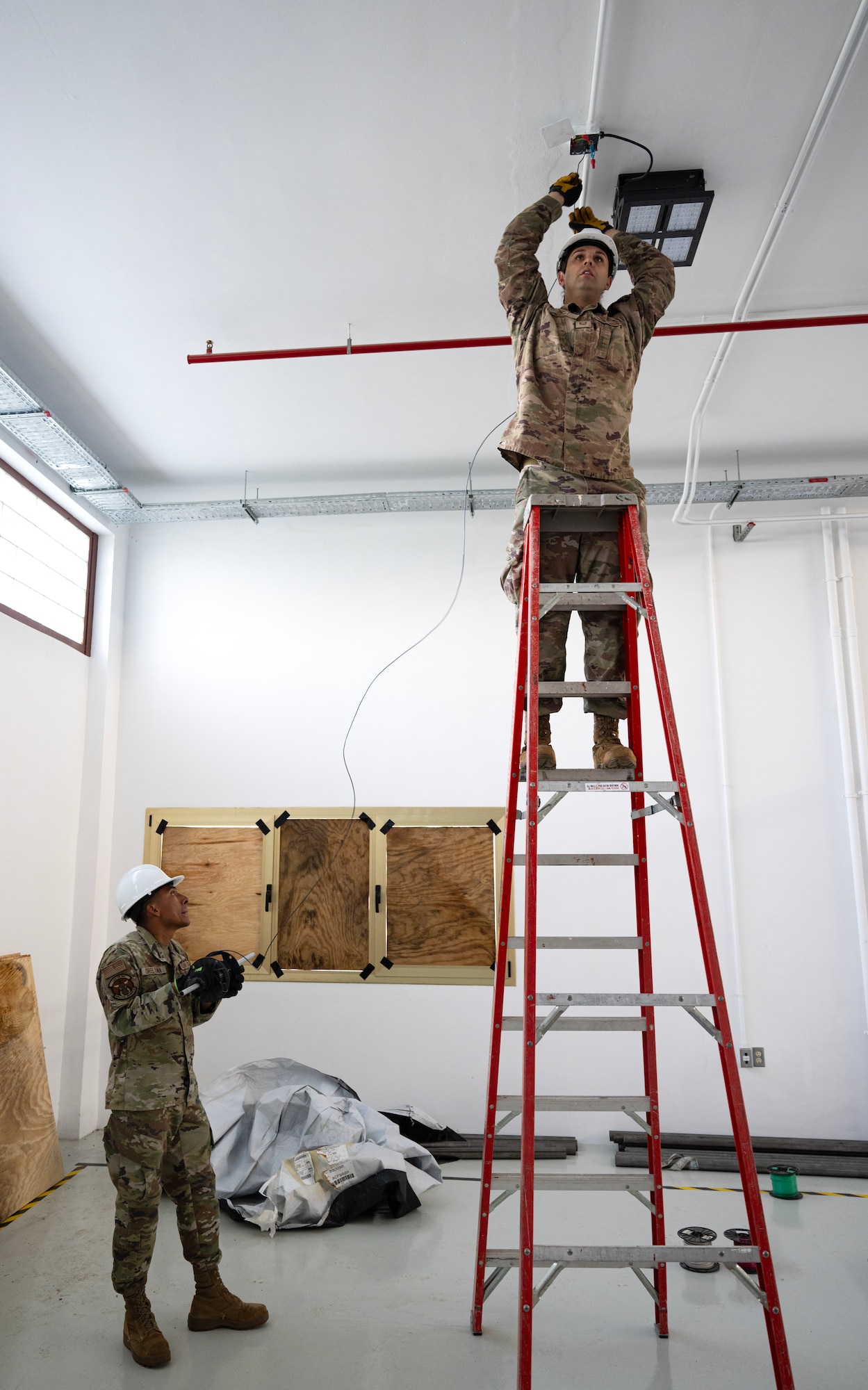 Tech. Sgt. Foster Grant, 446th Civil Engineer Squadron electrical system NCOIC, and Senior Airmen Alvarado Orellana, 446th CES electrical systems technician, lay electrical wire through pipes at Moron Air Base, Spain, on May 8, 2025.