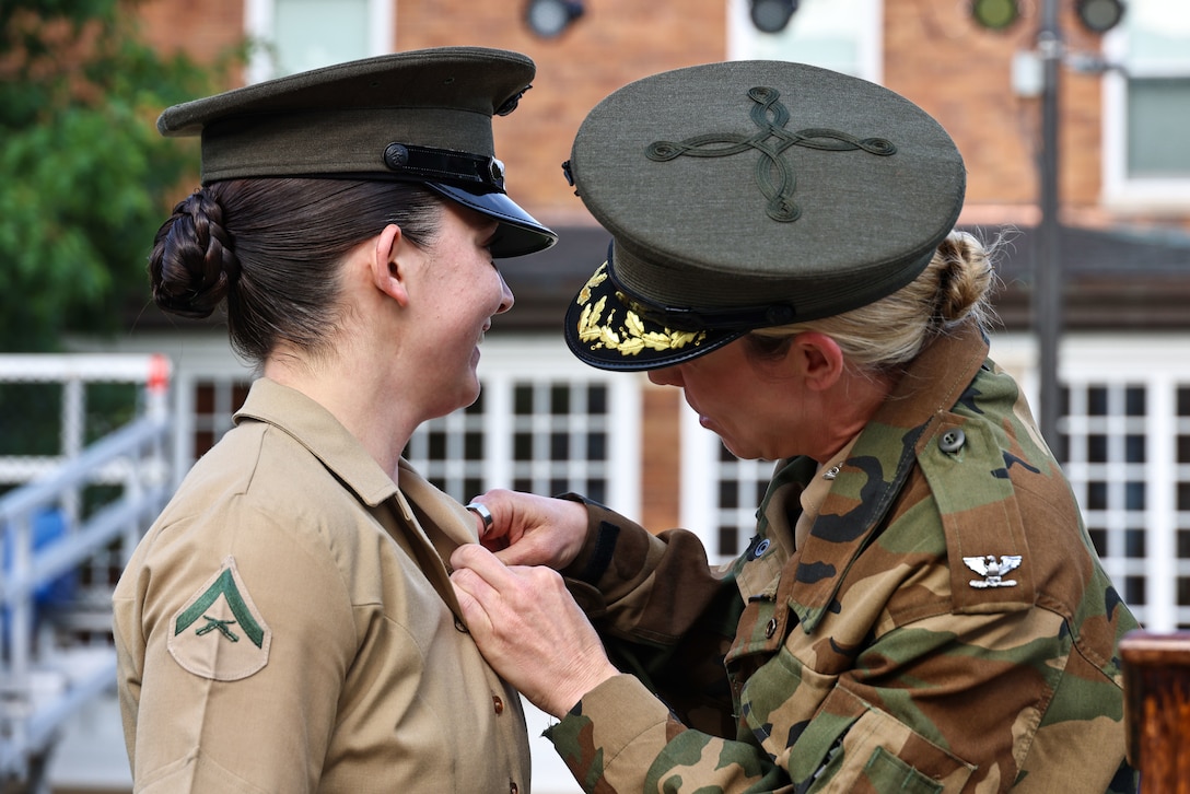 U.S. Marine Corps Col. Carrie Batson, commanding officer, Marine Barracks Washington, presents the Navy and Marine Corps Achievement Medal to Lance Cpl. Brynn Bouchard at Marine Barracks Washington, D.C., May 16, 2025. Lance Cpl. Bouchard was recognized for providing life-saving care to an individual experiencing a seizure last year. Once a month, a battalion formation is held to recognize the Marines of the "Oldest Post of the Corps" who have gone above and beyond in their service.