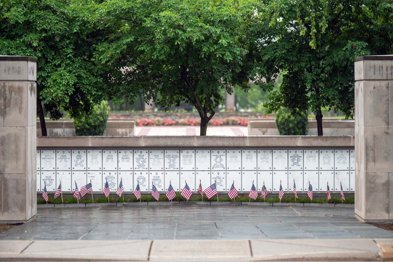Flags rest in front of columbarium walls at a memorial during an overcast day.