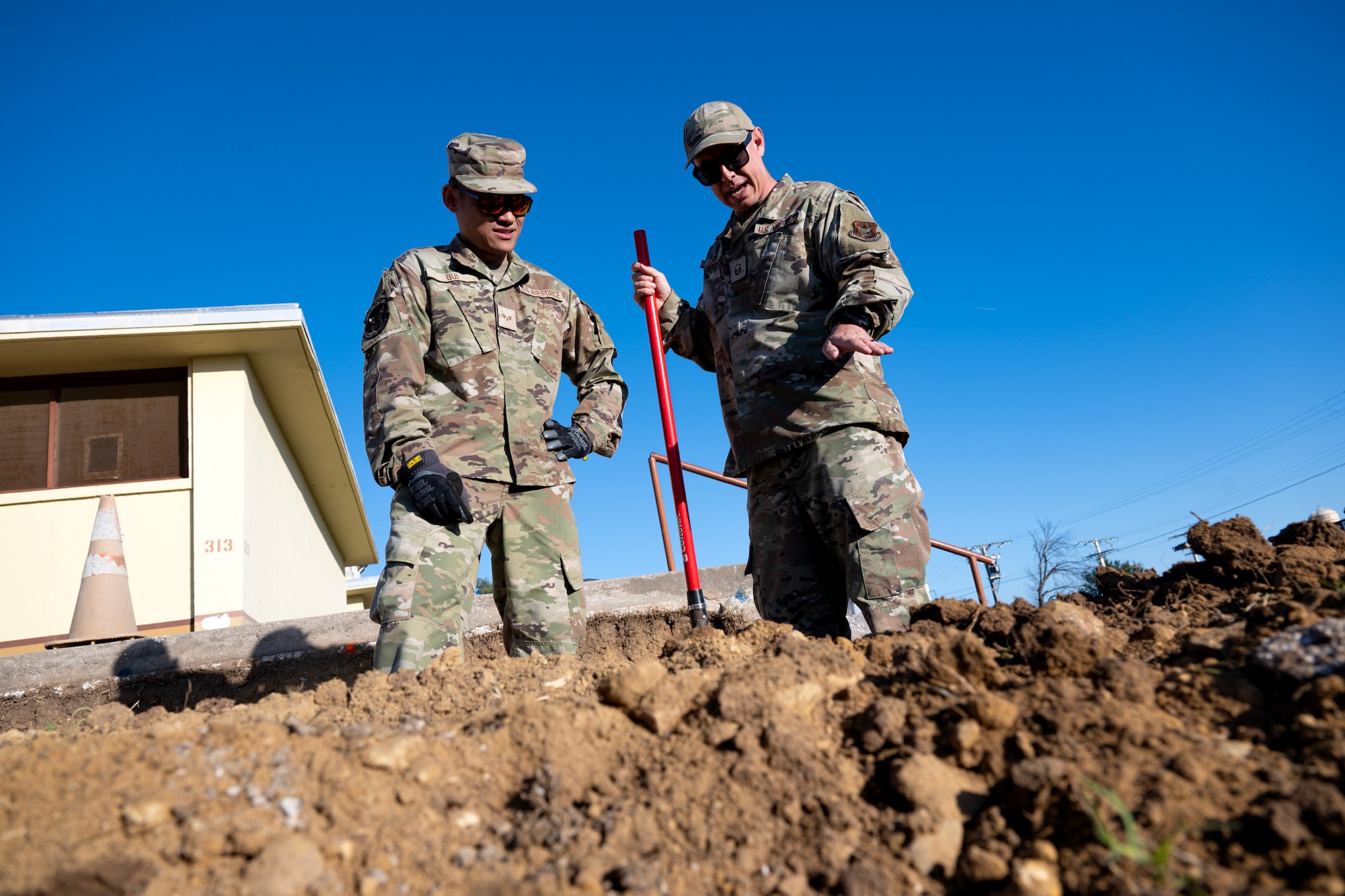Master Sgt. Matthew Smith, 446th Civil Engineer Squadron pavement and construction equipment NCOIC, instructs Airman 1st Class David Bui, 446th CES pavement and construction equipment technician, on the best techniques fore ensuring an accurate slope at Moron Air Base, Spain, on May 6, 2025.