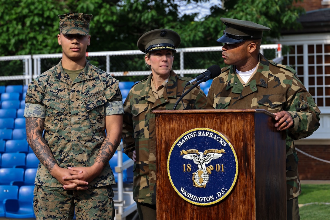 U.S. Marine Corps Cpl. Sean Thomas, Guard Company, Marine Barracks Washington stands to be recognized by Col. Carrie Batson, commanding officer, and Sgt. Maj. Jimmy Richard, sergeant major, at Marine Barracks Washington, D.C., May 16, 2025. Cpl. Thomas had assisted in administering life-saving care to a civilian in a medical emergency. Once a month, battalion formations are held to recognize the Marines of the "Oldest Post of the Corps" who have gone above and beyond in their service.
