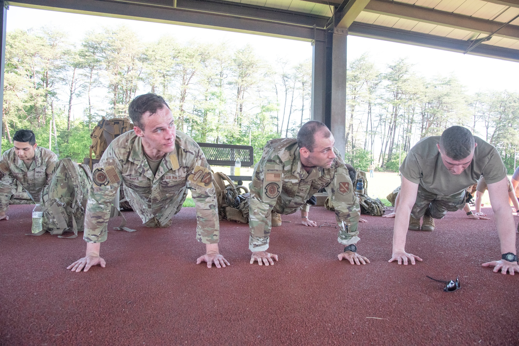 U.S. Airmen wait for Senior Master Sgt. Ashley R. Daniel, 816th Security Forces Squadron first sergeant, to read the names of 14 fallen security forces members before performing a pushup at Joint Base Andrews, Md., May 12, 2025. Airmen completed 14 pushups halfway through the 5-kilometer Fallen Defender Ruck. (U.S. Air Force photo by Patrick Griffith)
