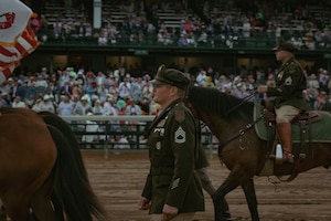 U.S. Army Sgt. 1st Class Timothy Nelson, a member of the1st Infantry Division's Commanding General's Mounted Color Guard, guides his team as they perform the Passing of the Colors at the Kentucky Derby racetrack, on May 3, 2025. This is the first year that U.S. Army horses have been invited to perform on track grounds since the Derby’s beginnings in 1875. (U.S. Army photo by Sgt. Tyler Selige)