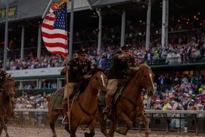 U.S. Army Sgt. Dakota Marrs and Spc. Tyler Boyer, members of the 1st Infantry Division's Commanding General's Mounted Color Guard, charge off the field after performing the Passing of the Colors during the Kentucky Derby, on May 3, 2025. This is the first year that U.S. Army horses have been invited to perform on track grounds since the Derby’s beginnings in 1875. (U.S. Army photo by Sgt. Tyler Selige)