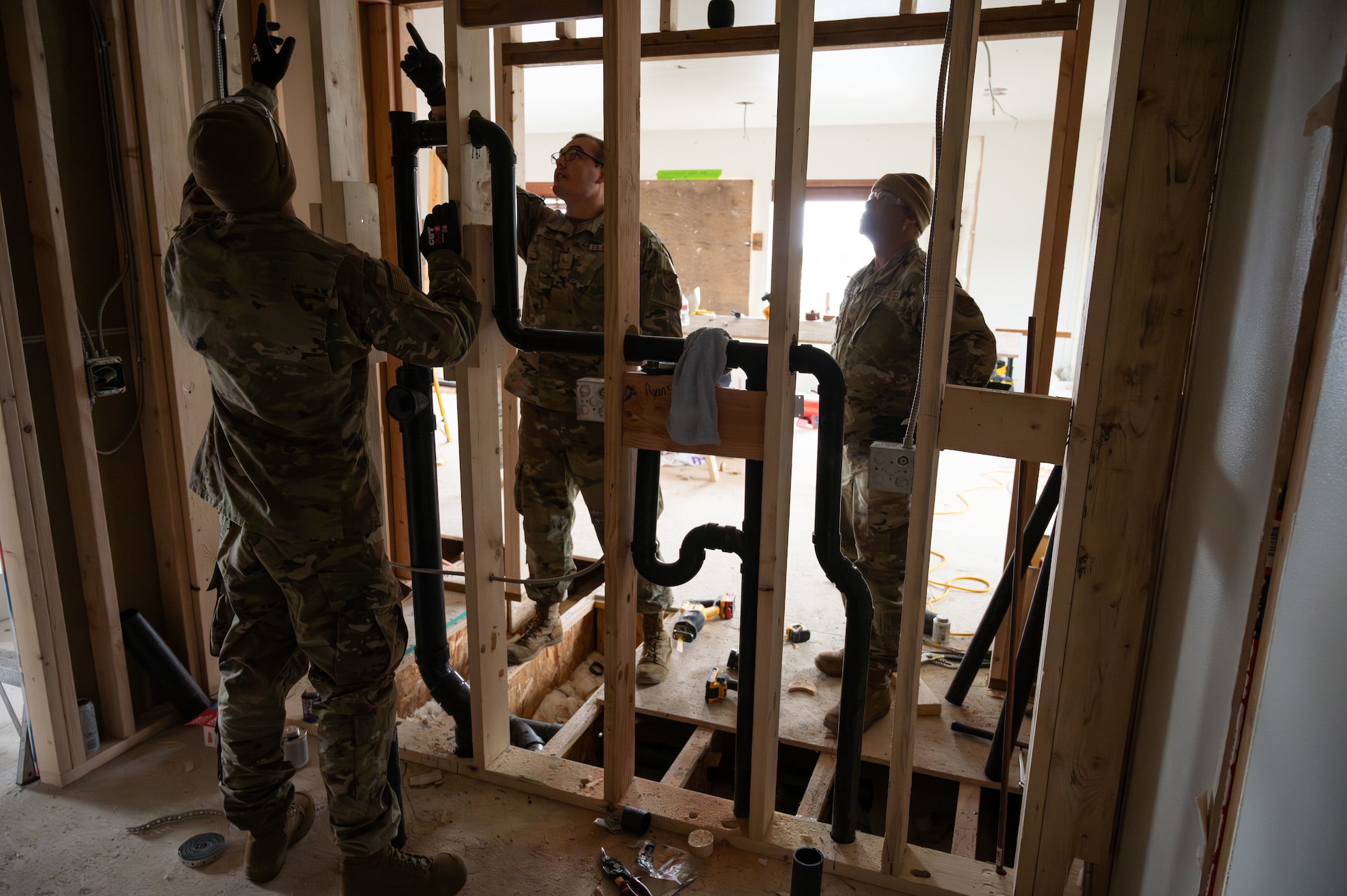 Tech. Sgt. Ryan Speicher, 131st Civil Engineer Squadron (CES) heavy equipment operator journeyman, and Senior Airman Anthony Rocca, water and fuel systems maintenance journeyman, discuss plumbing layout as Tech. Sgt. Adrian Doss, structures journeyman, looks on during a deployment for training in Seward, Alaska, April 26, 2025. 131st CES Airmen deployed to Alaska as part of an ongoing partnership with the Seward Military Resort, which allows military units to train while updating structures and infrastructure on location. (U.S. Air National Guard photo by Senior Airman Kelly C. Ferguson)