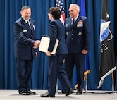 Cadet receives award on stage with Air Force leadership.
