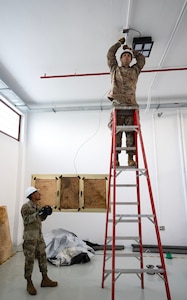 Tech. Sgt. Foster Grant, 446th Civil Engineer Squadron electrical system NCOIC, and Senior Airmen Alvarado Orellana, 446th CES electrical systems technician, lay electrical wire through pipes at Moron Air Base, Spain, on May 8, 2025.