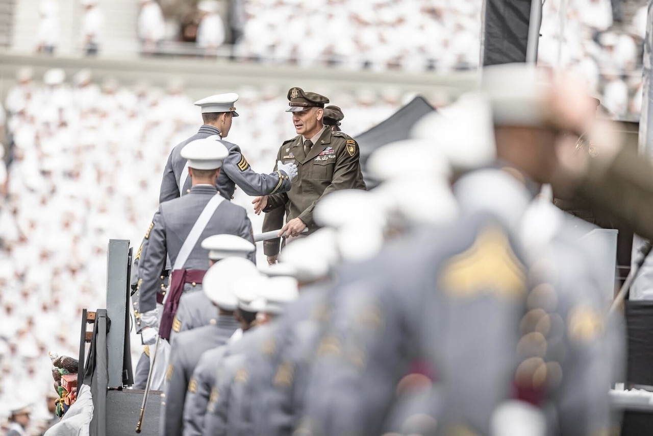 Graduates of the U.S. Military Academy walk across a stage.