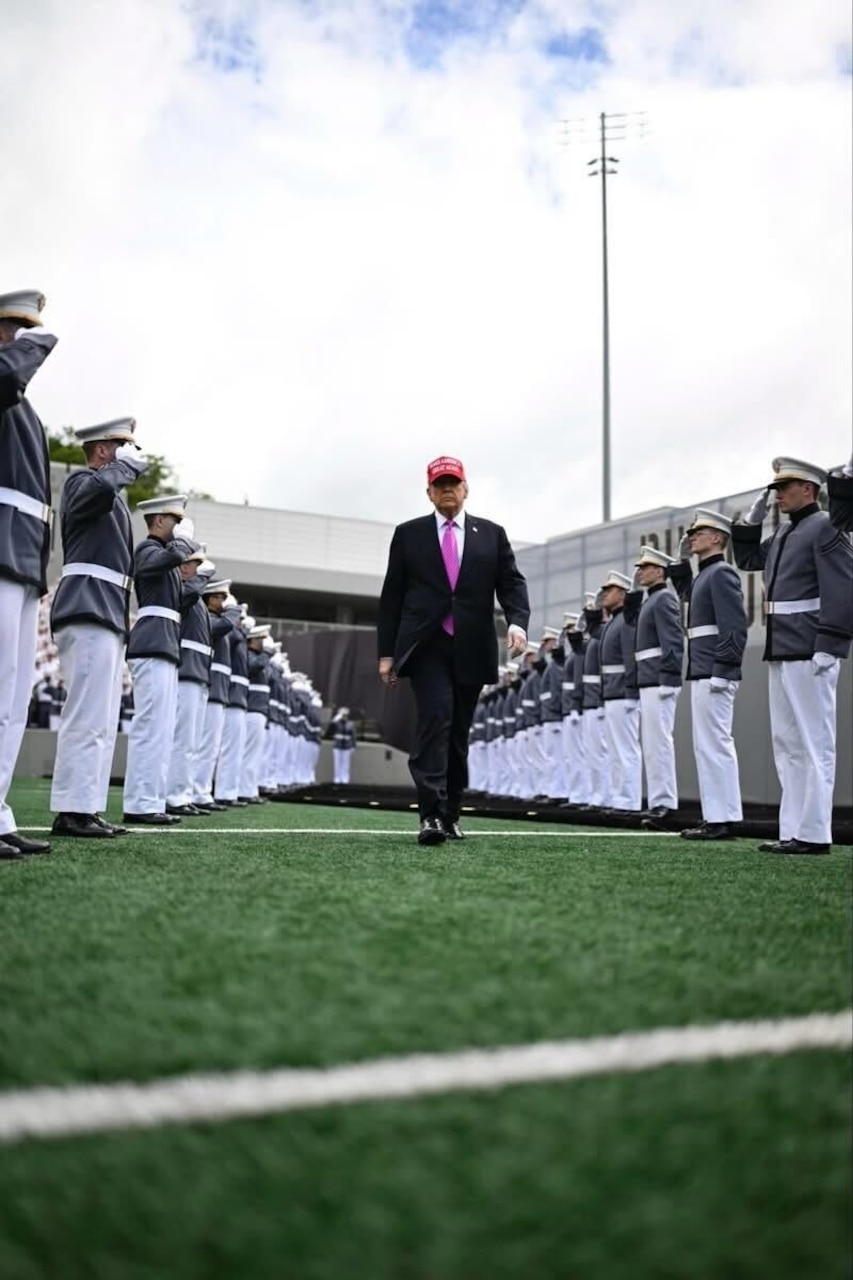 The president walks down the center of graduates.