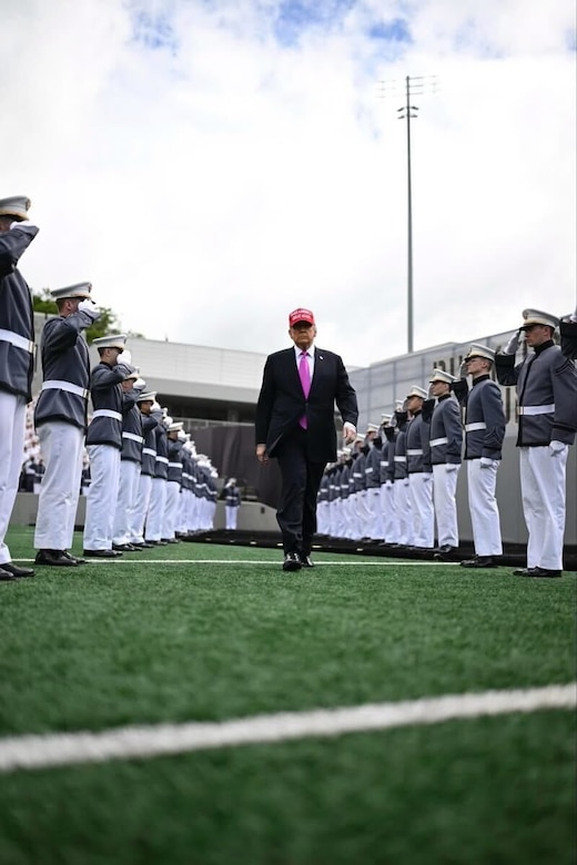The president walks down the center of graduates.