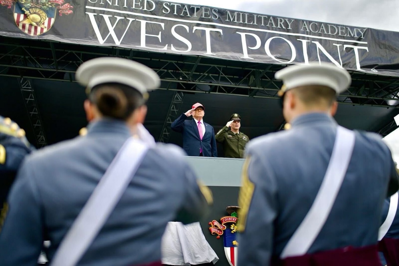 The president salutes while standing on a stage as cadets watch.