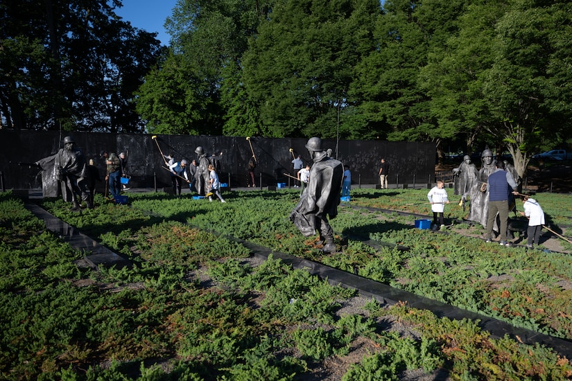 The defense secretary and volunteers clean statues.