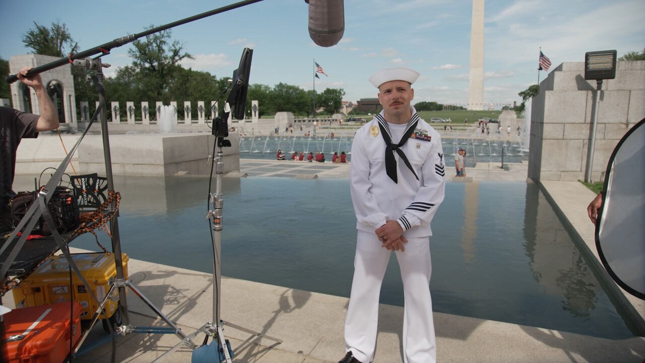 A sailor stands at a monument.