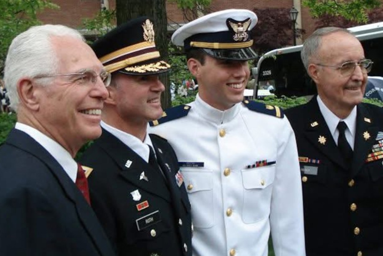 Four men stand smiling.