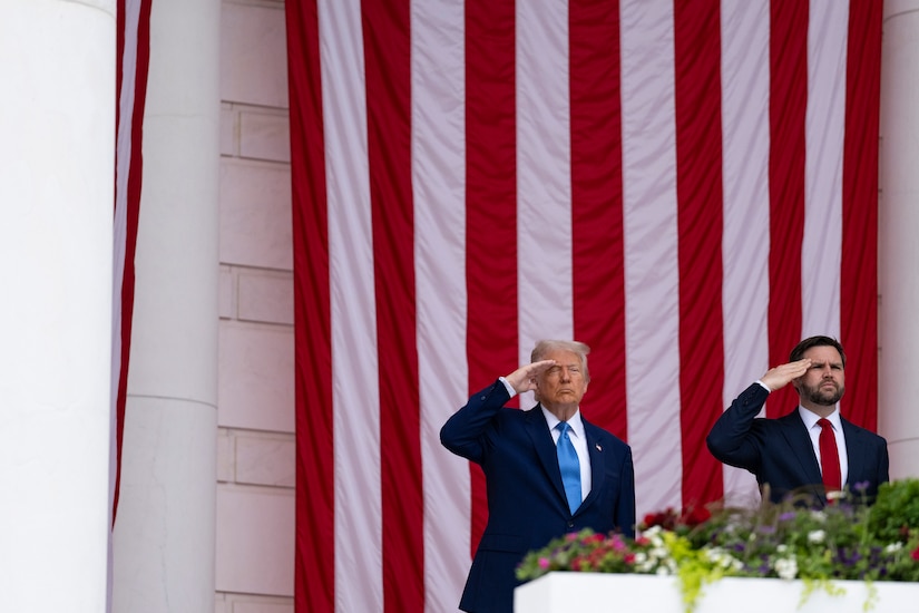 The president and vice president salute in front of an American flag.