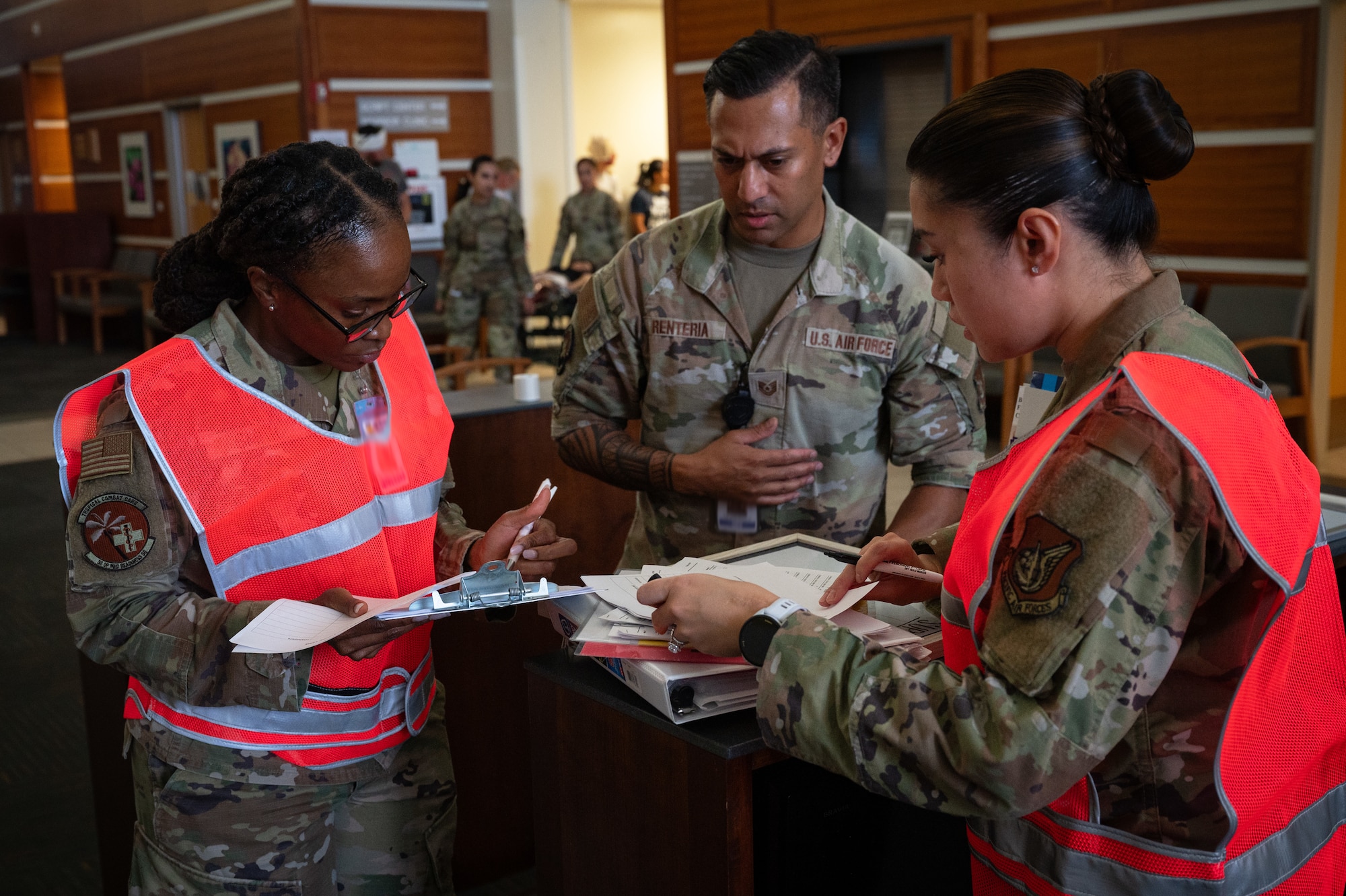 (From left) Major Winnebelle Smith, Tech. Sgt Andy Renteria, and Capt. Anne Gielyn Auer, in-processing team, review patient information during a Mass Casualty Exercise at Andersen Air Force Base, Guam, May 14, 2025. This exercise simulated a hostile attack with multiple casualties of varying injuries. The final part of the exercise was the simulation of getting the injured to the correct departments that would be best able to provide specialized care for that individual. With multiple casualties and lives on the line, efficiency, communication and teamwork are crucial to this task. (U.S. Air Force photo by Staff Sgt. Pedro Tenorio)