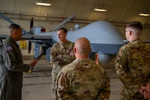 An Airman briefs the PACAF commander in front of an MQ-9 during an immersion tour.