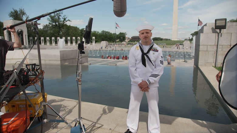 A sailor stands at a monument.
