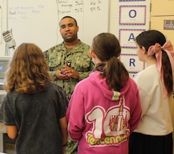 Hospital Corpsman Second Class (HM2) Luis Morales, Laboratory Technician, captivated students with examples of germs and bacteria viewed under a microscope, discussing the intricacies and importance of laboratory work in diagnosing and monitoring patient health. He touched on the variety of specimens analyzed in the lab, including blood, urine, and other bodily fluids. The conversation with HM2 Morales sparked a lively exchange as several students shared their personal experiences of providing blood and other lab specimens, creating a relatable connection and highlighting the role the lab plays in their own healthcare journeys.