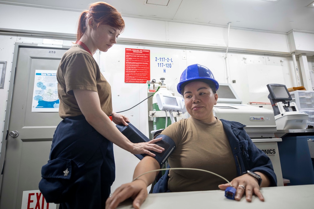250507-N-PX933-2126 NORFOLK, Va. (May 7, 2025) Hospital Corpsman 2nd Class Kindal Kidd, left, takes Machinist's Mate Fireman Lorena Toscano’s blood pressure aboard the Nimitz-class aircraft carrier USS Dwight D. Eisenhower (CVN 69). Eisenhower is moored at Norfolk Naval Shipyard for a Planned Incremental Availability maintenance period. (U.S. Navy photo by Mass Communications Specialist Seaman Jahlen Williams)