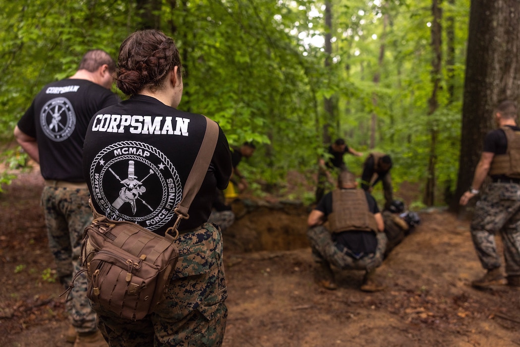 250513-M-ML869-1187 U.S. Navy Corpsman HM3 Andrea Gibeck, with the Martial Arts Instructor Trainer Course 2-25, observes sparring during the “Fighting Holes” training event at The Basic School on Marine Corps Base Quantico, May 13, 2025. Squads engaged head-to-head inside of fighting holes simulating close quarter combat while implementing techniques learned within the Marine Corps Martial Arts Program. (U.S. Marine Corps photo by Lance Cpl. Harleigh Faulk)