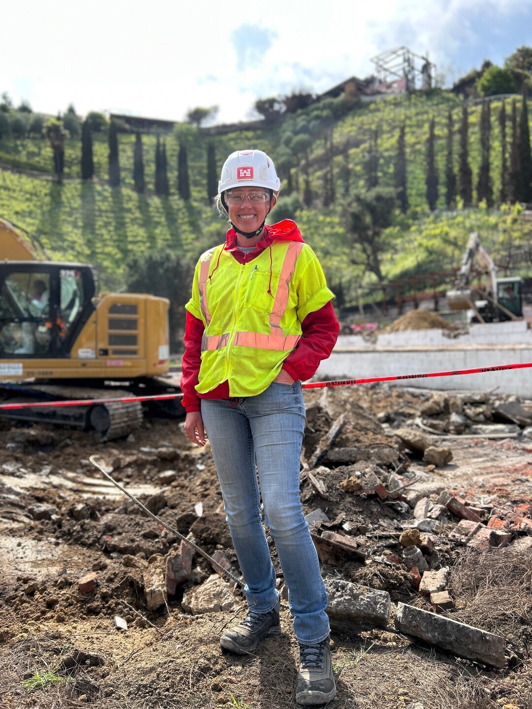 Woman wearing hard hat and safety vest at recovery site.
