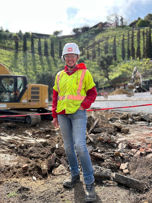 Woman wearing hard hat and safety vest at recovery site.