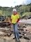 Woman wearing hard hat and safety vest at recovery site.