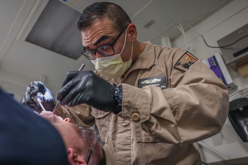 ATLANTIC OCEAN (May 20, 2025) Cmdr. Jonathan Negron (right), from Port Saint Lucie, Florida inspects the condition of the teeth of Senior Chief Hospital Corpsman Bryan Clarke, from Whittier, California, inside a dental exam room aboard the Wasp-class amphibious assault ship USS Iwo Jima (LHD 7). Iwo Jima Amphibious Ready Group (ARG) and 22nd Marine Expeditionary Unit (MEU) are underway in the Atlantic Ocean completing integrated naval warfighting training. ARGMEUEX prepares integrated naval task forces for sustained, high-end Joint and combined combat. Integrated naval training provides combatant commanders and the Commander-in-Chief highly capable forces that deter adversaries, underpin American security and economic prosperity, and reassure Allies and partners. (U.S. Navy photo by Mass Communication Specialist 2nd Class Joseph T. Miller)