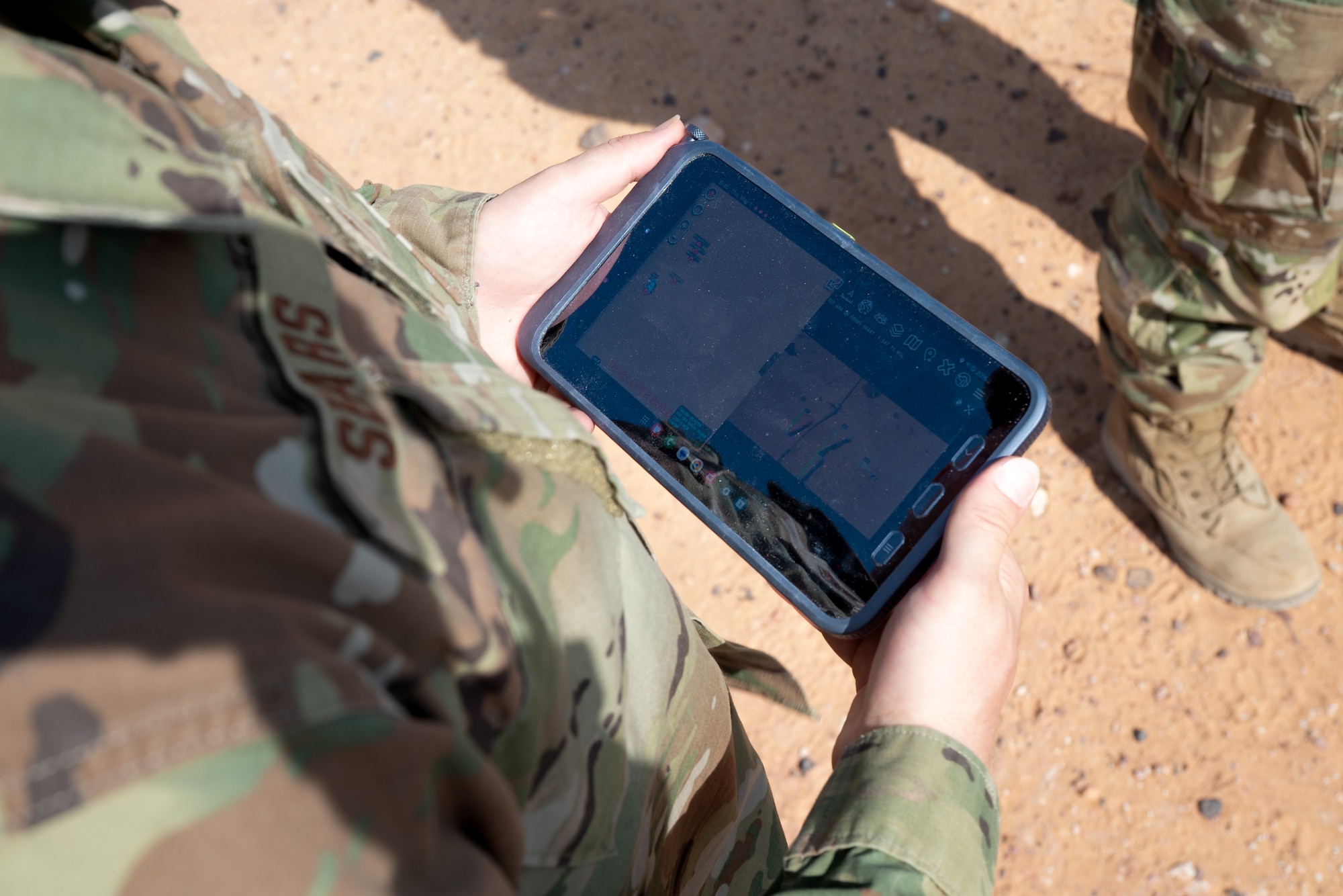 Airman holds a tablet that is showing the live feed from a drone camera