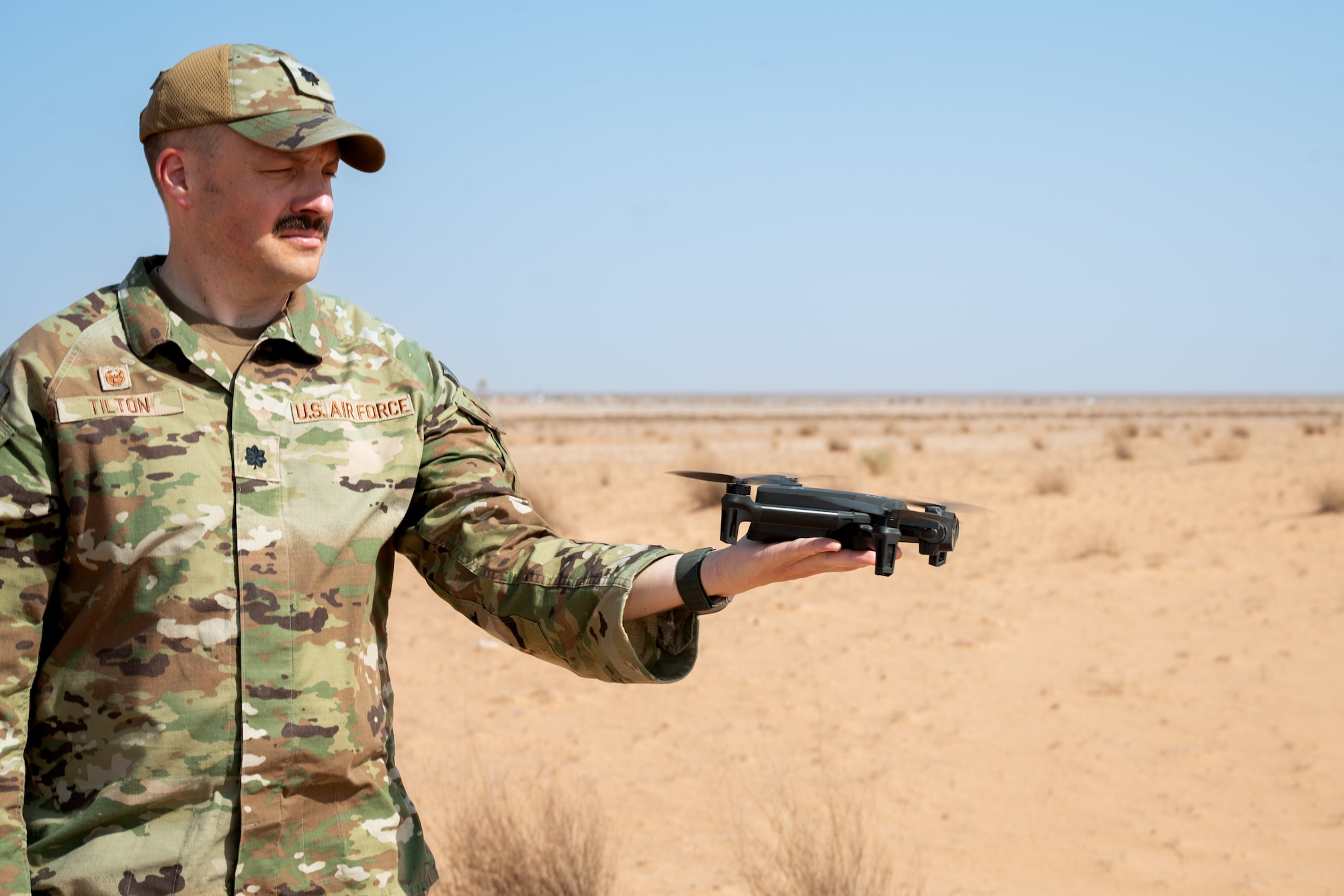Airman holds a drone before it takes flight