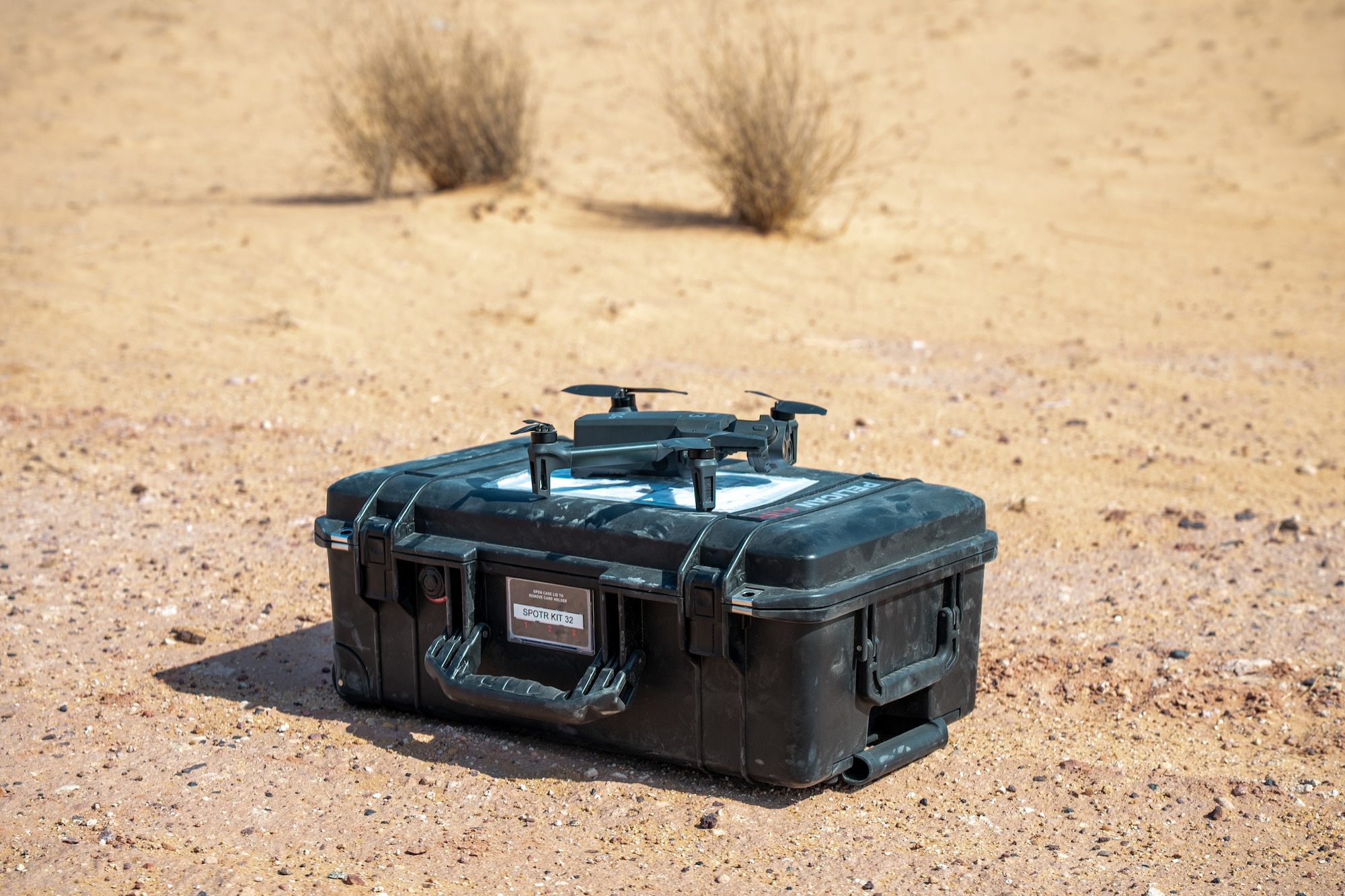 A drone sits on a Pelican Case in the desert