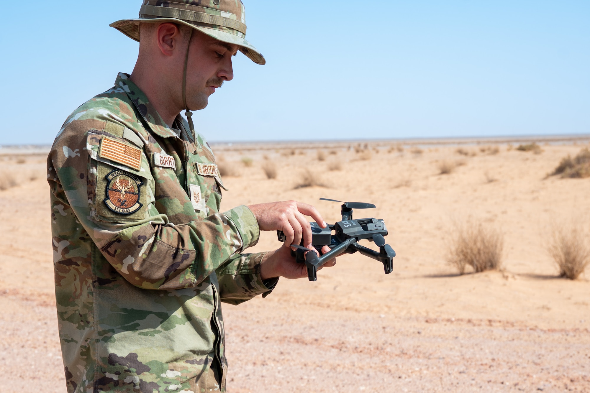 Airman replaces a battery pack on a drone in the desert