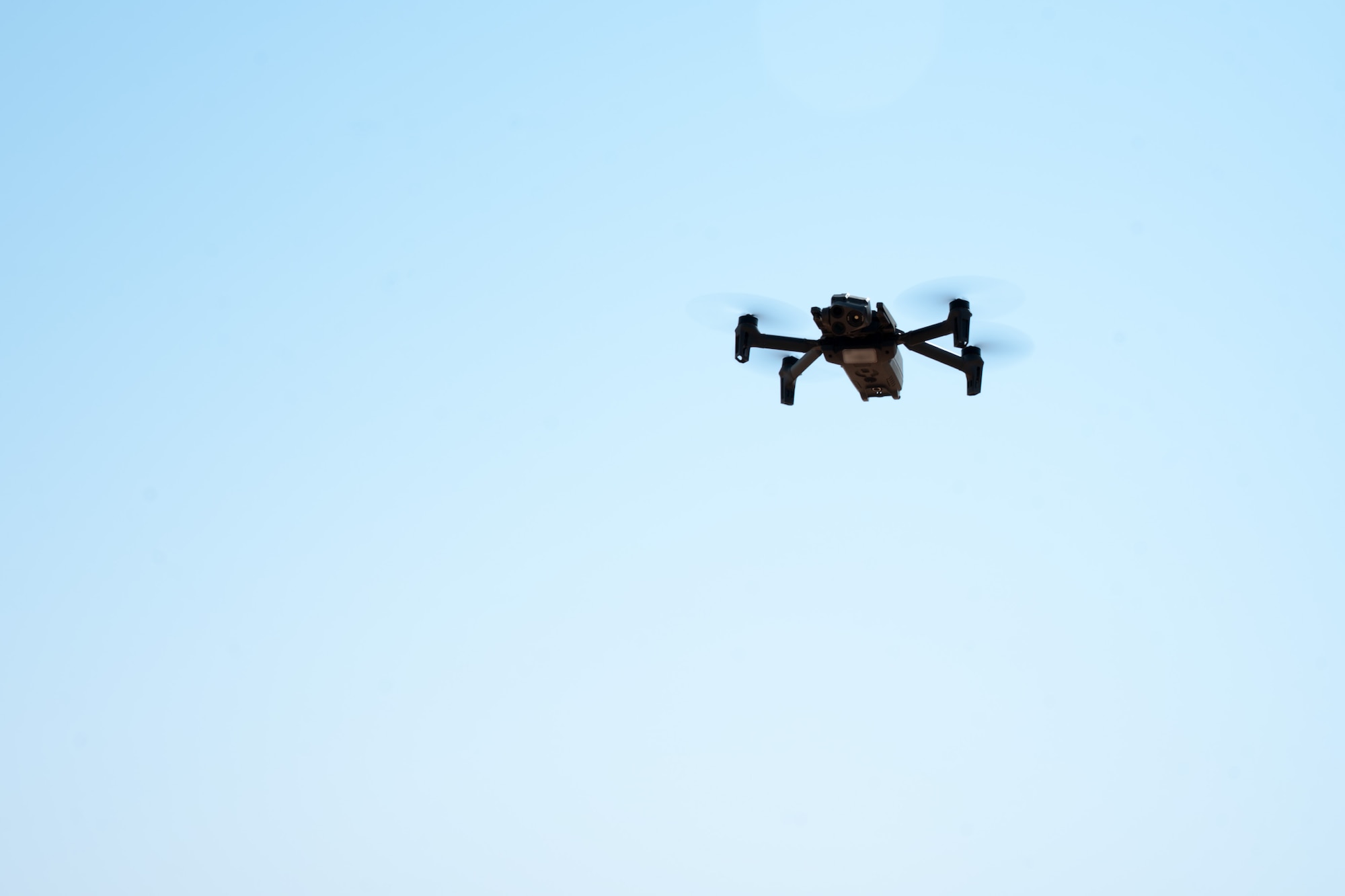 A drone flying in front of a blue sky