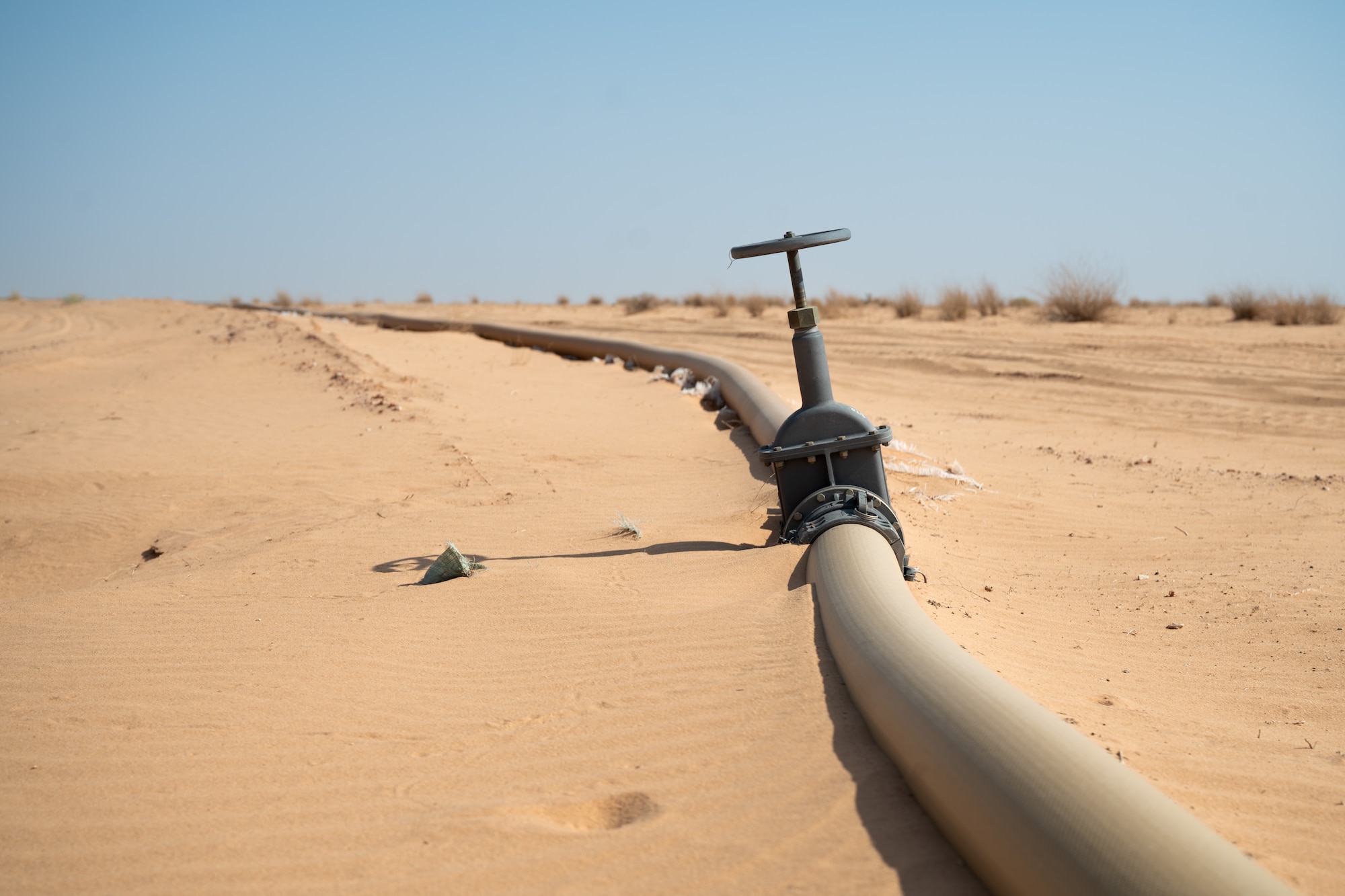 A fuel line sits on the desert floor