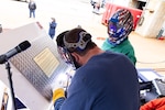 The sponsor of DDG 132, Madison Ann Zolper, who is the great-granddaughter of Quentin Walsh, strikes welding sparks into a keel plate inscribed with her initials. At left is BIW welder Eric Goldsmith who assisted the sponsor.