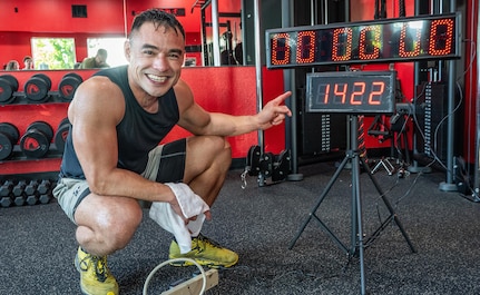 A sweat-soaked Oregon Army National Guard Physician Assistant Maj. Tommy Vu points to the counter displaying 1,422 repetitions after completing his world record attempt for most hand release push-ups in one hour at West Coast Strength gym in West Salem, Ore., May 23, 2025.