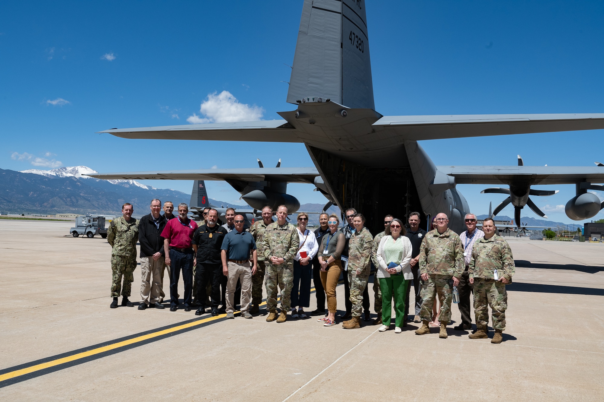 A group photo behind a military aircraft.