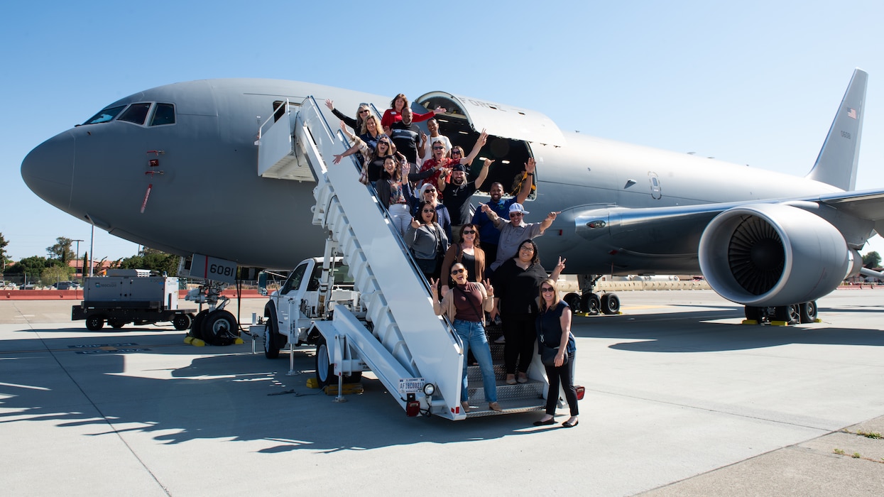 Local leadership pose for a group photo outside an aircraft on the flight line