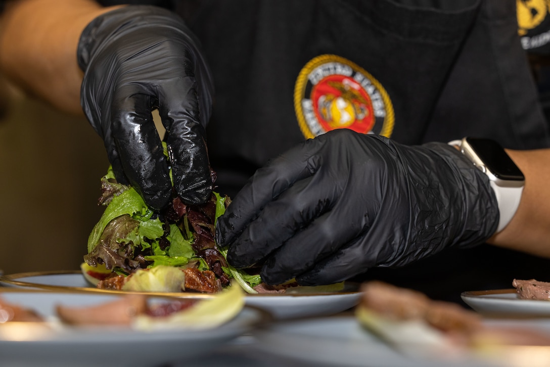 U.S. Marine Corps Cpl. Kevona Kelly, trainee in the Marine Corps Enlisted Aide Program, garnishes a salad for a luncheon hosted by the Marine Corps Enlisted Aide Program on March 28, 2025 at Marine Barracks Washington, D.C. Marine Corps Enlisted Aide trainees are currently attending the Bullock Estate Training Service (B.E.S.T.) course, and must successfully host a luncheon in order to graduate the course. Each luncheon features a different guest list, ranging from staff noncommissioned officers to commissioned officers and civilians. These luncheons are a key part of their training curriculum, allowing Marines to plan, execute, and present formal meals for official military events.