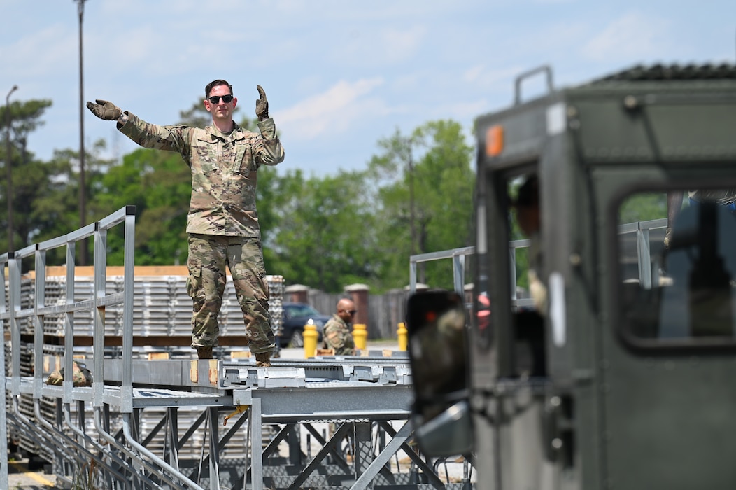 U.S. Air Force Senior Airman Zechariah Gerardi, 87th Aerial Port Squadron ramp representative apprentice, guides in a 60K vehicle using hand signals at Joint Base Charleston, S.C., April 10, 2025. APS Airmen practice guiding and operating the vehicles for hours to help ensure efficiency and comfortability. (U.S. Air Force photo by Tech. Sgt. Joel McCullough)