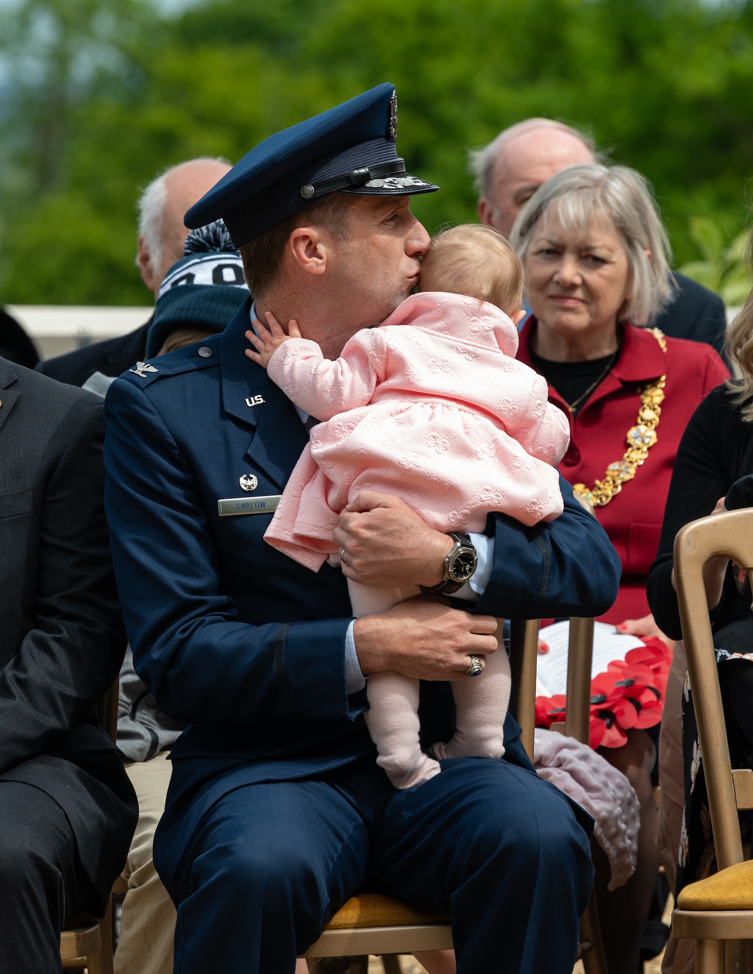 U.S. Air Force Col. Ryan Garlow, 100th Air Refueling Wing commander, kisses his daughter during the Memorial Day ceremony at the Cambridge American Cemetery and Memorial in Cambridge, England, May 26, 2025.