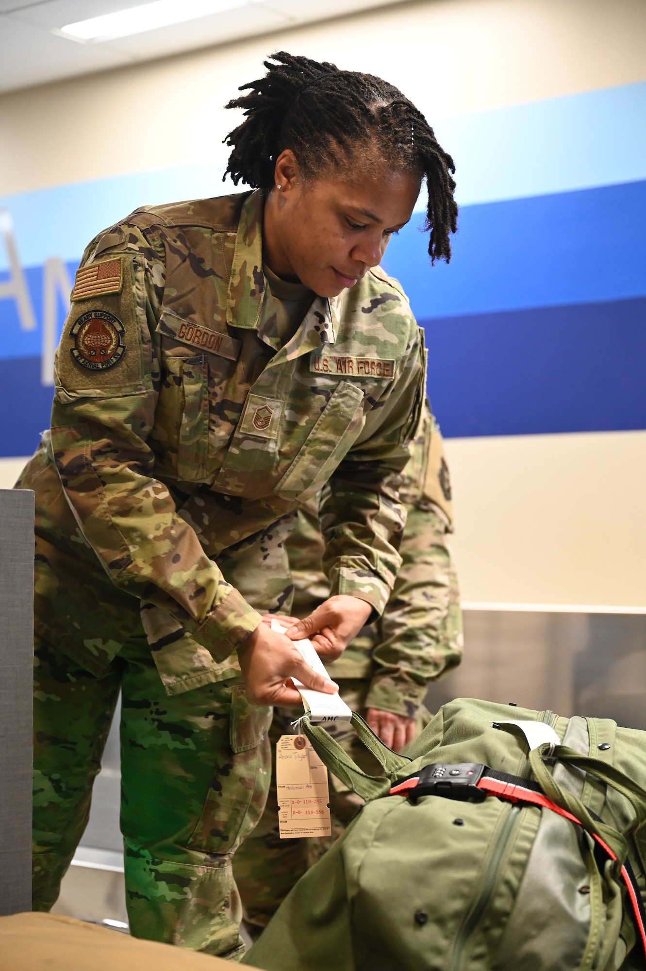 U.S. Air Force Master Sgt. Bakiden Gordon, 87th Aerial Port Squadron passenger services representative craftsman, tags a bag after checking in an Airman at the passenger terminal at Joint Base Charleston, S.C., April 9, 2025. The 437th APS, the active-duty unit, workload has increased due to maintenance of another unit's runway. Training alongside active-duty members not only provides training for Reservists but relief and help for the active-duty missions. (U.S. Air Force photo by Tech. Sgt. Joel McCullough)