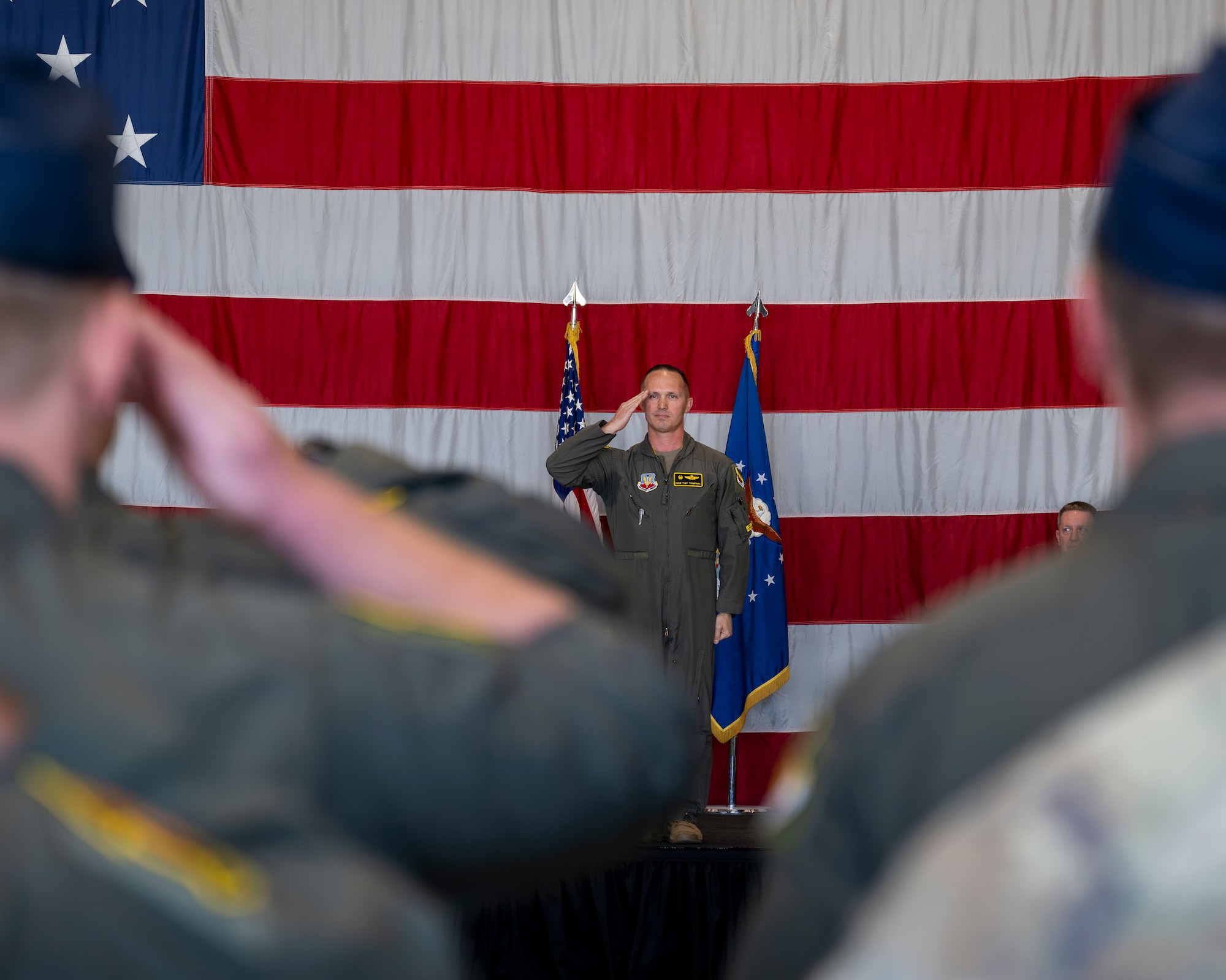 A photo of a commander in front of an American flag, saluting his Airmen for the first time