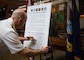 WASHINGTON (May 5, 2025) - Rear Adm. David Faehnle, commandant, Naval District Washington, signs a Gold Star Remembrance proclamation at the Navy Museum onboard the Washington Navy Yard. The Navy Gold Star Program provides support to surviving family members of Sailors who died while on active duty, regardless of your loved one's military branch, location, or manner of death. (U.S. Navy Photo by Mass Communication Specialist 1st Class Griffin Kersting)