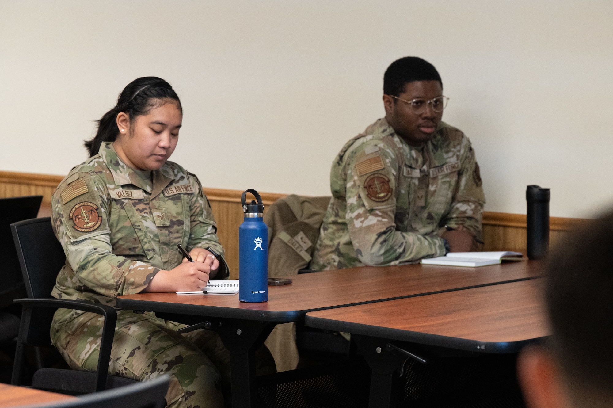 Two Airmen takes notes during a training session.